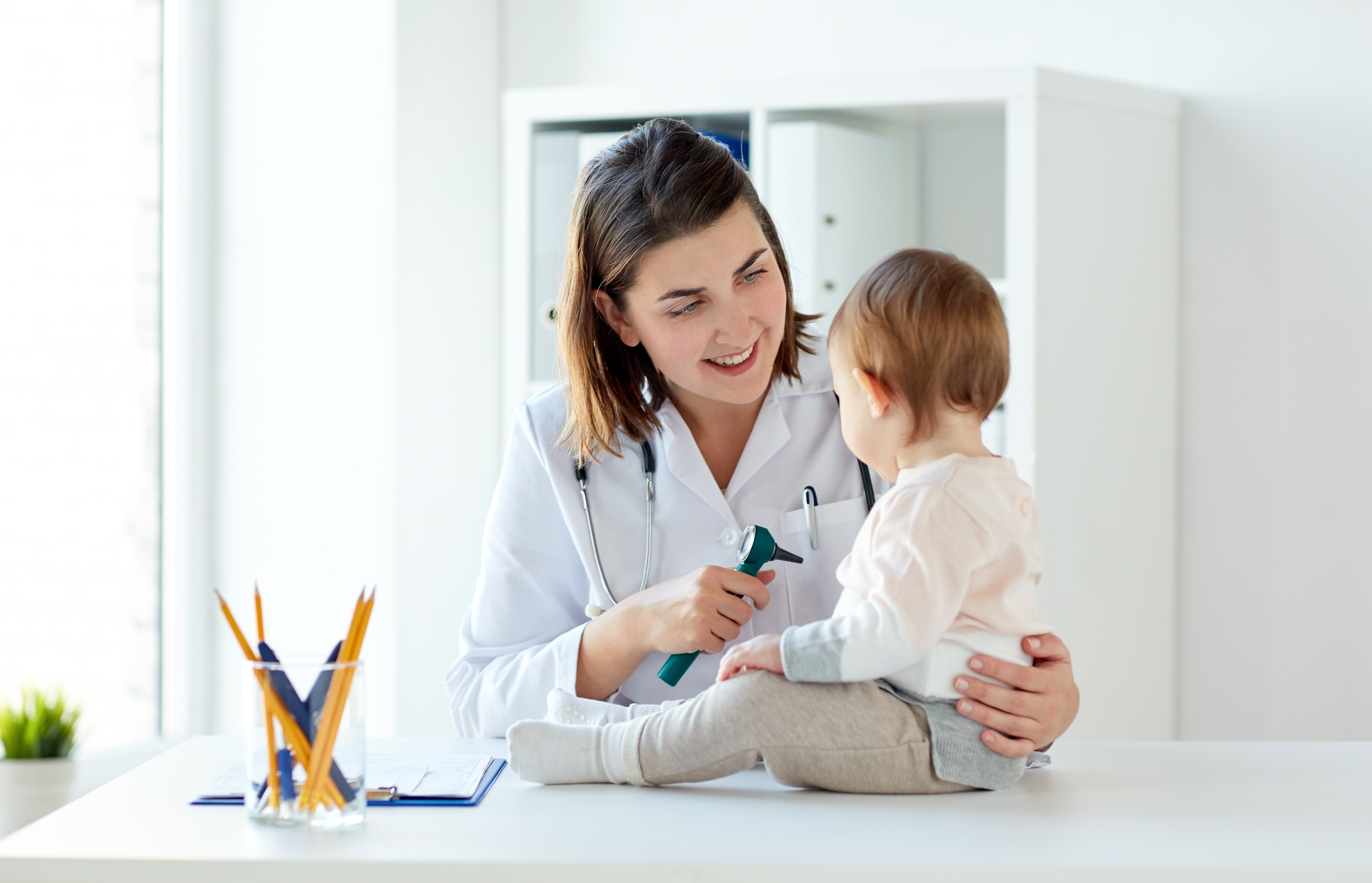 doctor with baby and otoscope at clinic